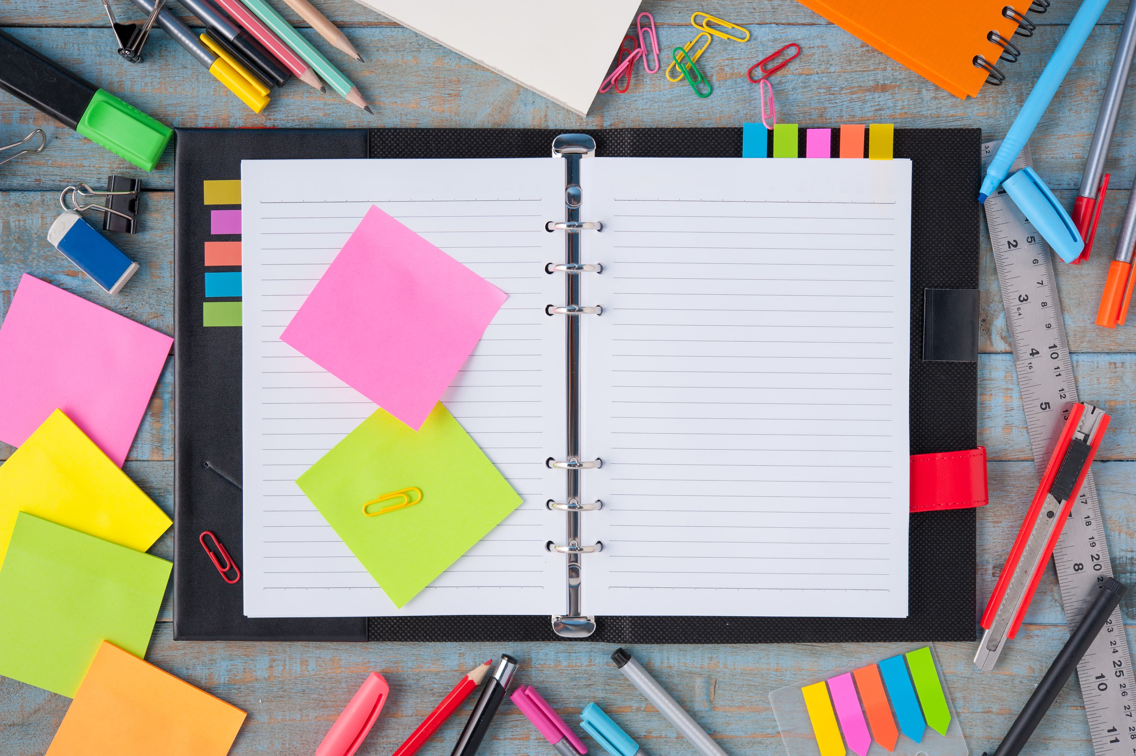 Caderno aberto com ícones de trânsito coloridos e marca-texto para anotações de estudo